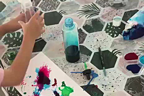 Mains d'enfant saisissant un vaporisateur d'eau pour en spritzer sur sa feuille