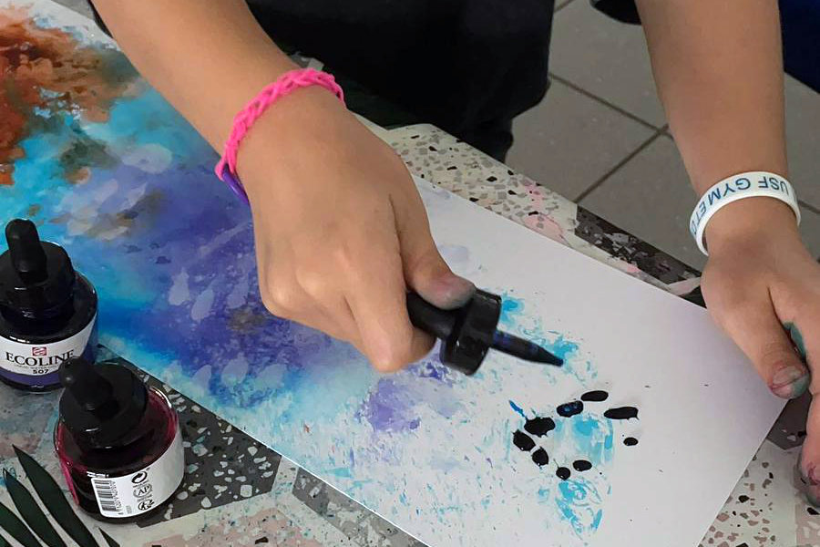 Main d'enfant appliquant de l'encre sur sa feuille