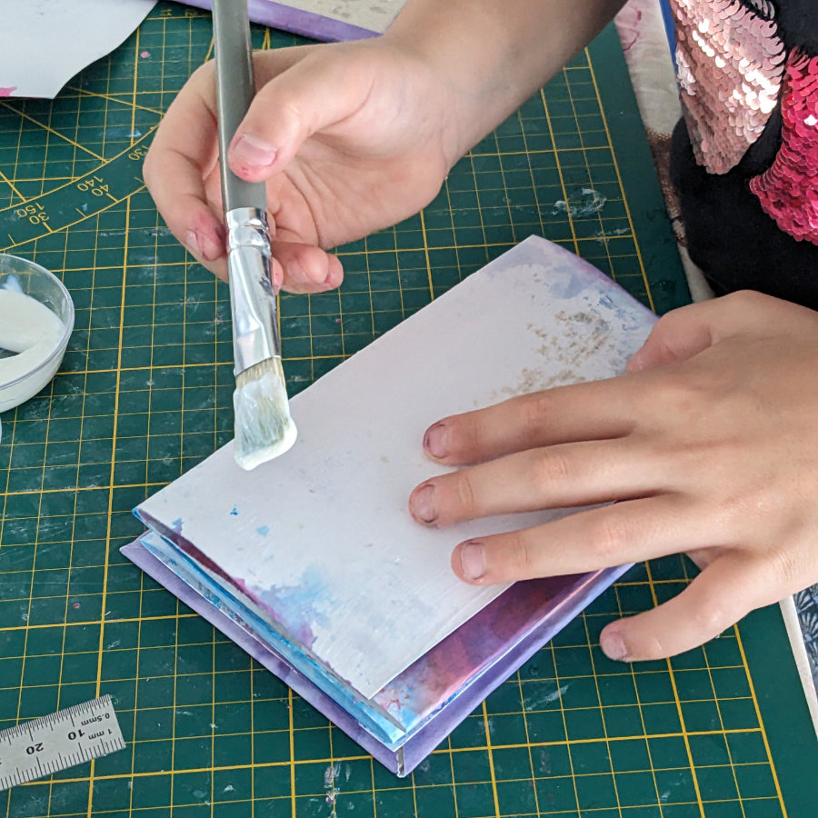 Mains d'enfant appliquant de la colle sur une extrémité de l'accordéon